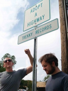 Photo by Catherine Rierson. Musician Ari Picker and Trekky Recordsâ€™ Martin Anderson show off Trekkyâ€™s new Adopt-A-Highway sign, which can be found on North Greensboro Street.
